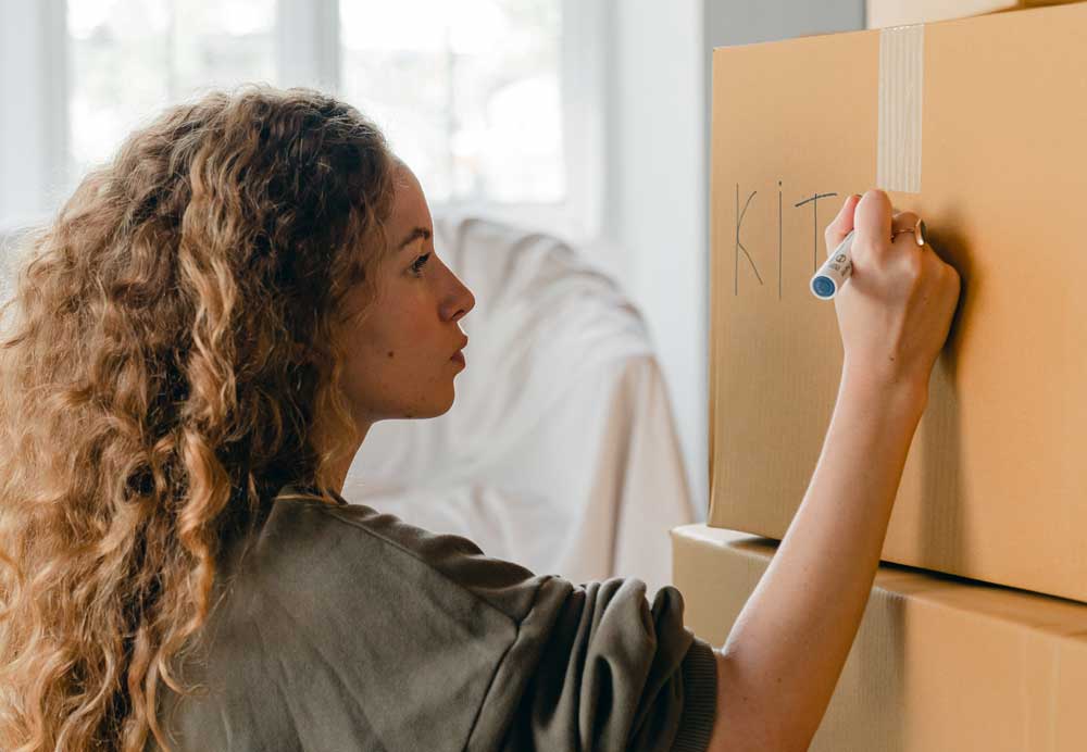 woman writing on moving box