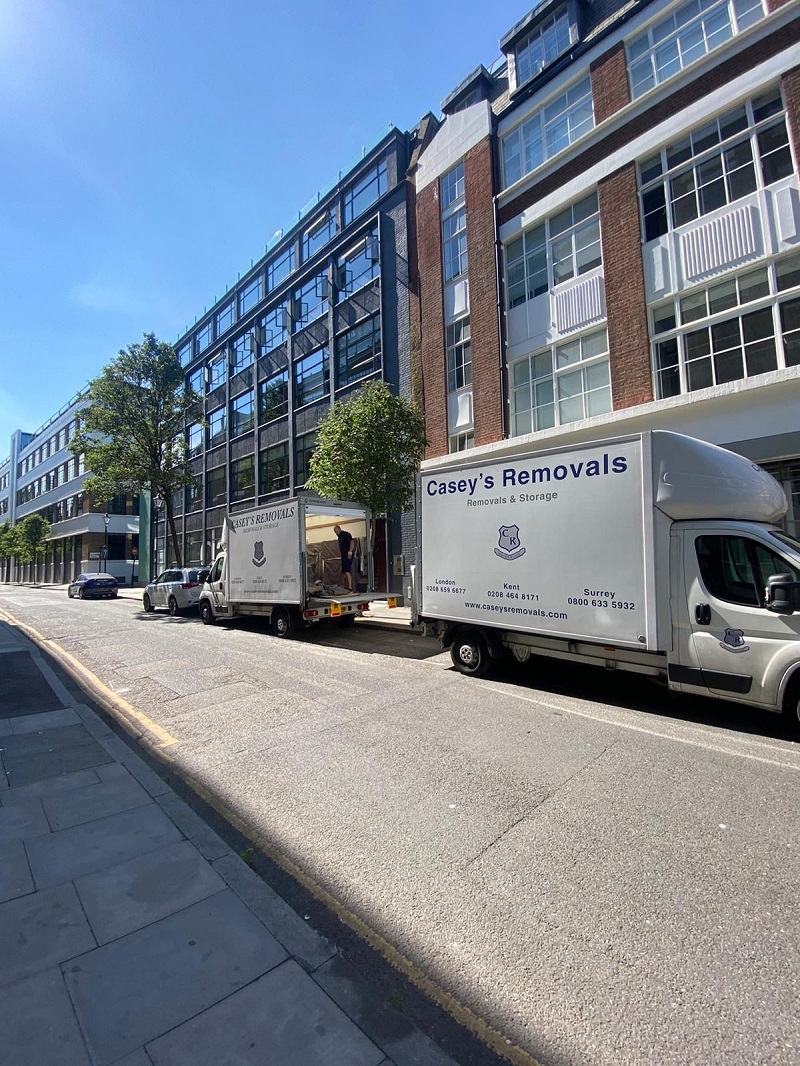 White removals trucks with casey's removals printed on side parked outside office building in London