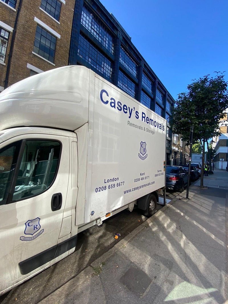 White luton van with casey's removals printed on side parked outside office building in London