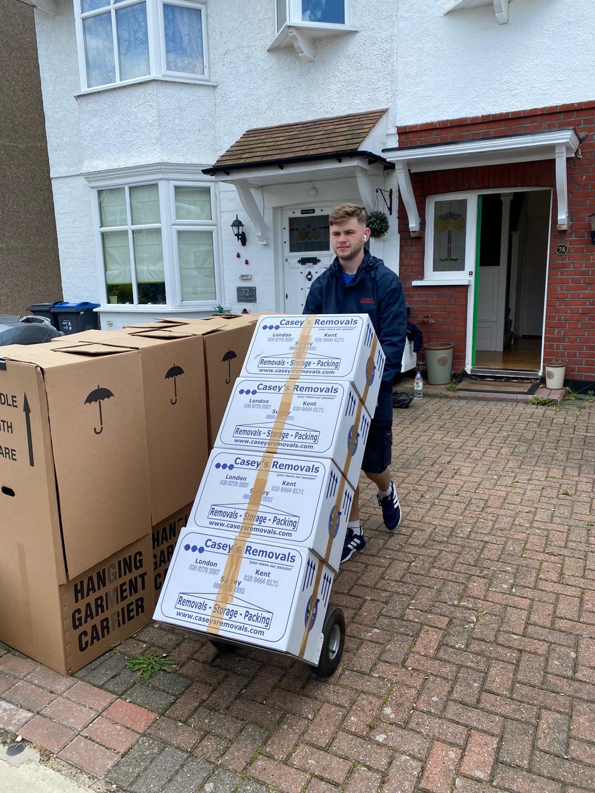 Removal man moving casey's removal boxes on trolley outside out